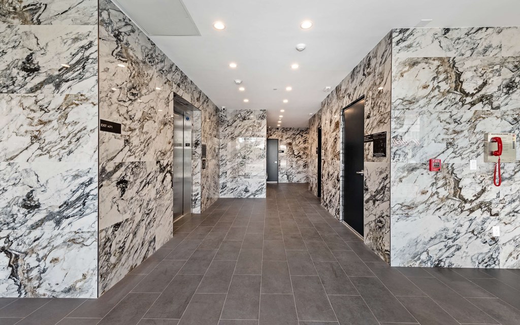 a view of the elevators in the lobby of a building with marble walls and floors