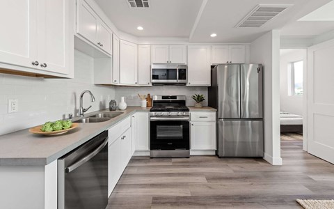 a white kitchen with stainless steel appliances and white cabinets