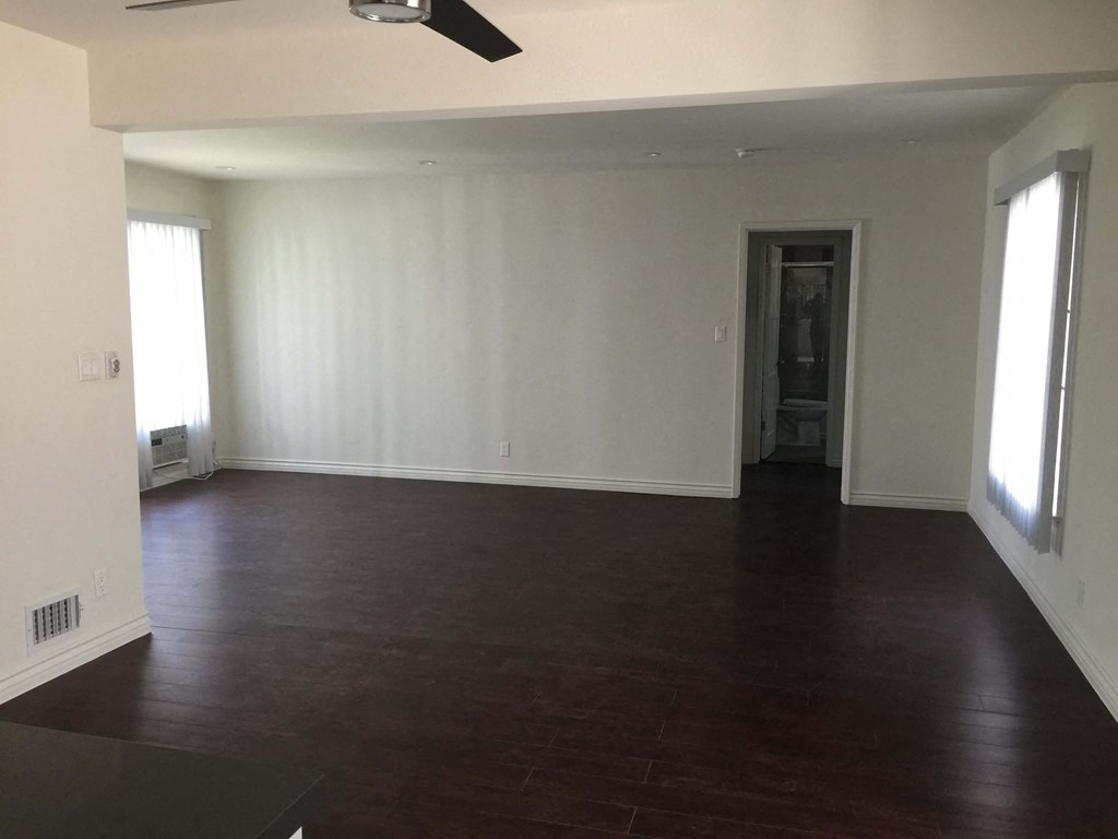 an empty living room with white walls and a dark wood floor