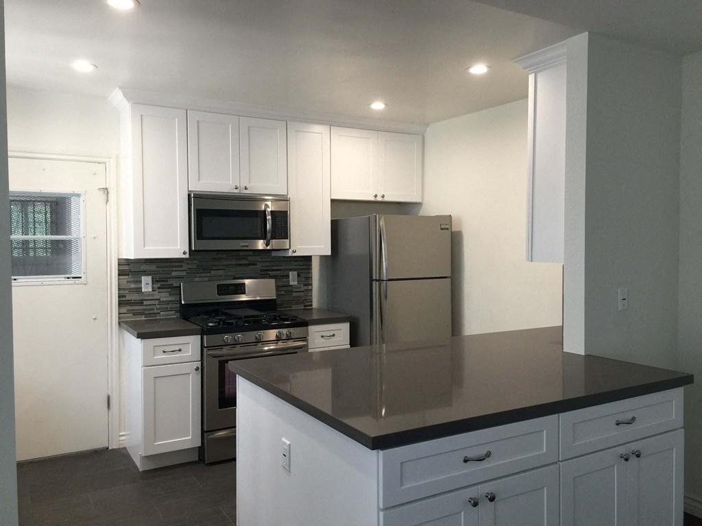 a kitchen with white cabinets and a black counter top