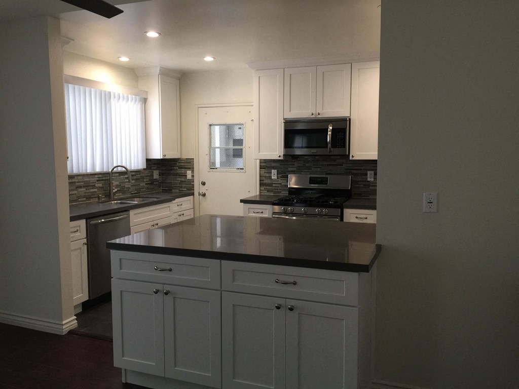 a kitchen with white cabinets and a black counter top