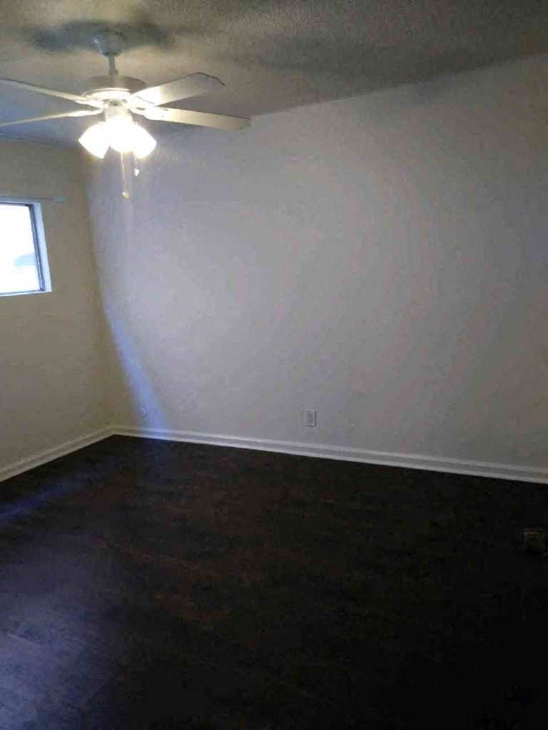 an empty room with a ceiling fan and a window