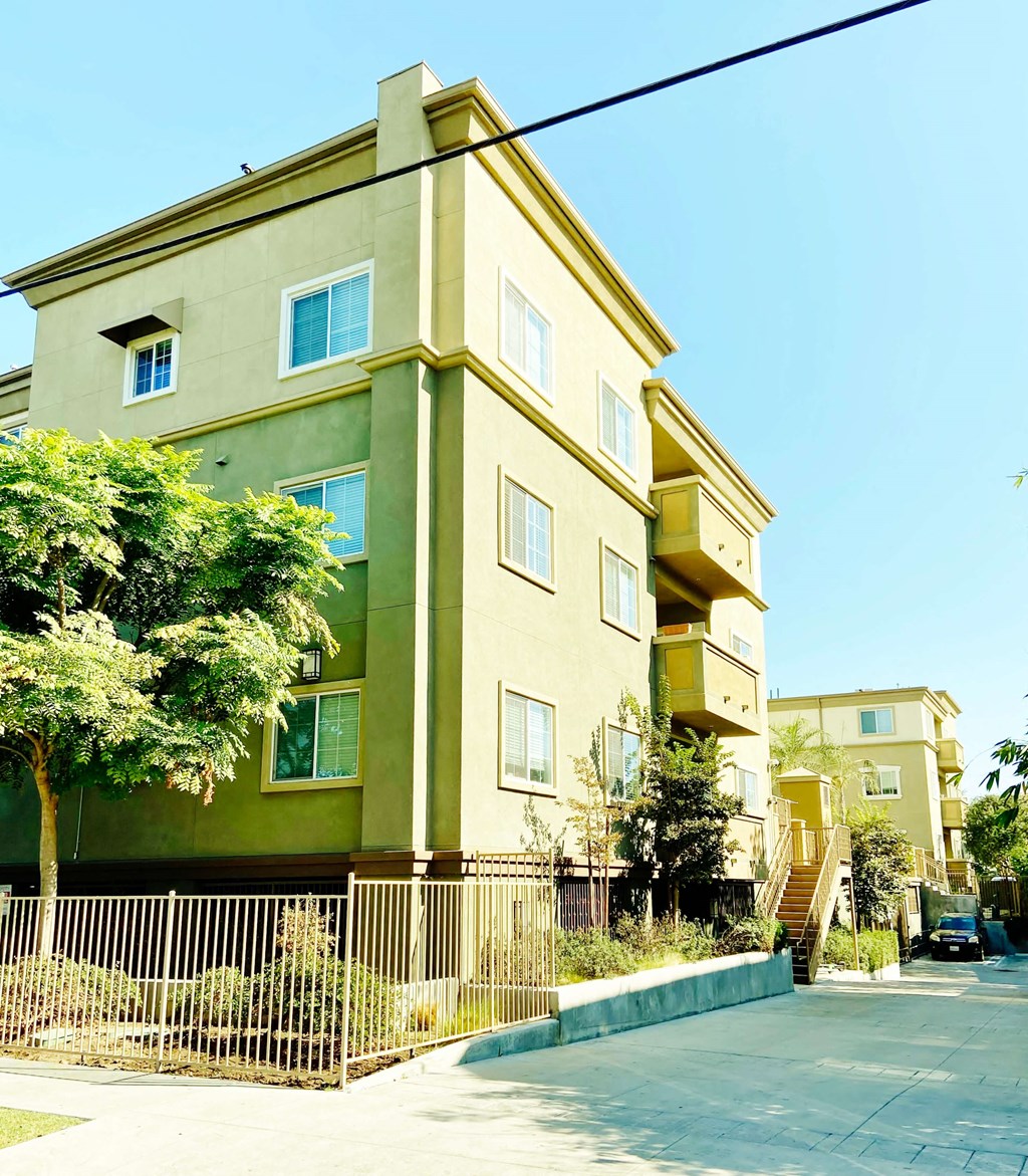 a yellow and green apartment building with trees in front of it
