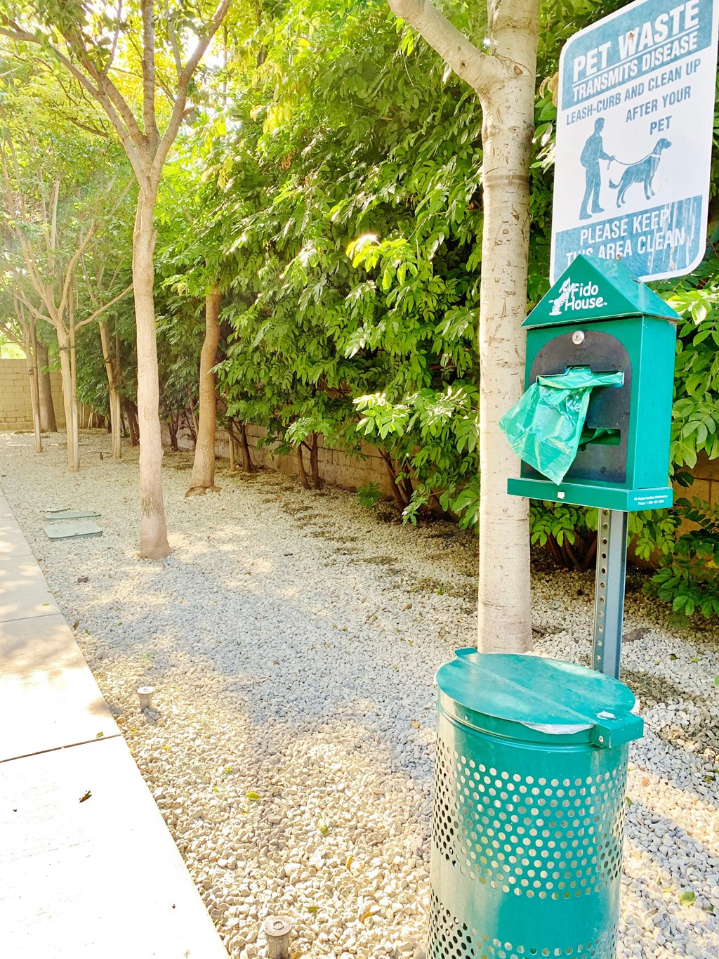 a green trash can sitting next to a tree