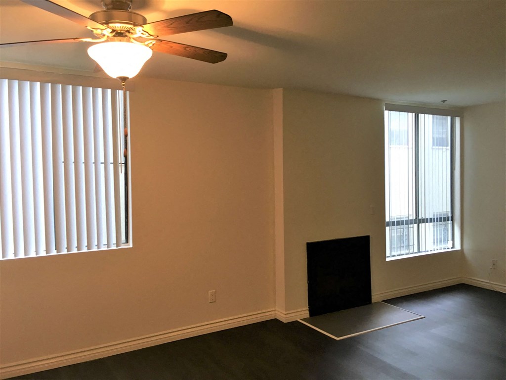 a living room with two windows and a ceiling fan