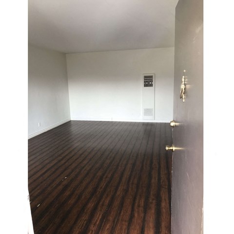 a bedroom with hardwood floors and white walls