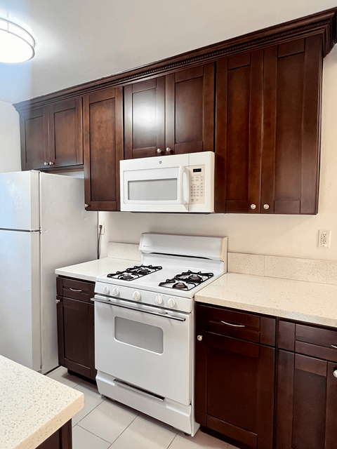 a kitchen with white appliances and dark wood cabinets