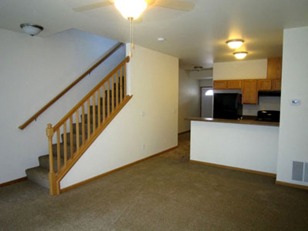 a living room with a staircase and a kitchen