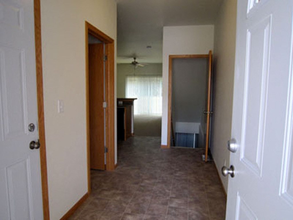 a hallway with two doors and a kitchen in the background