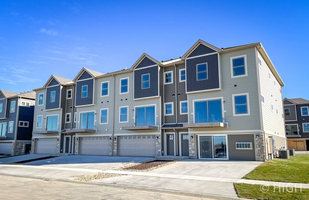an apartment building with blue windows and a driveway