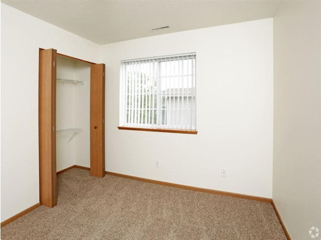 a bedroom with a large window and a door to a closet