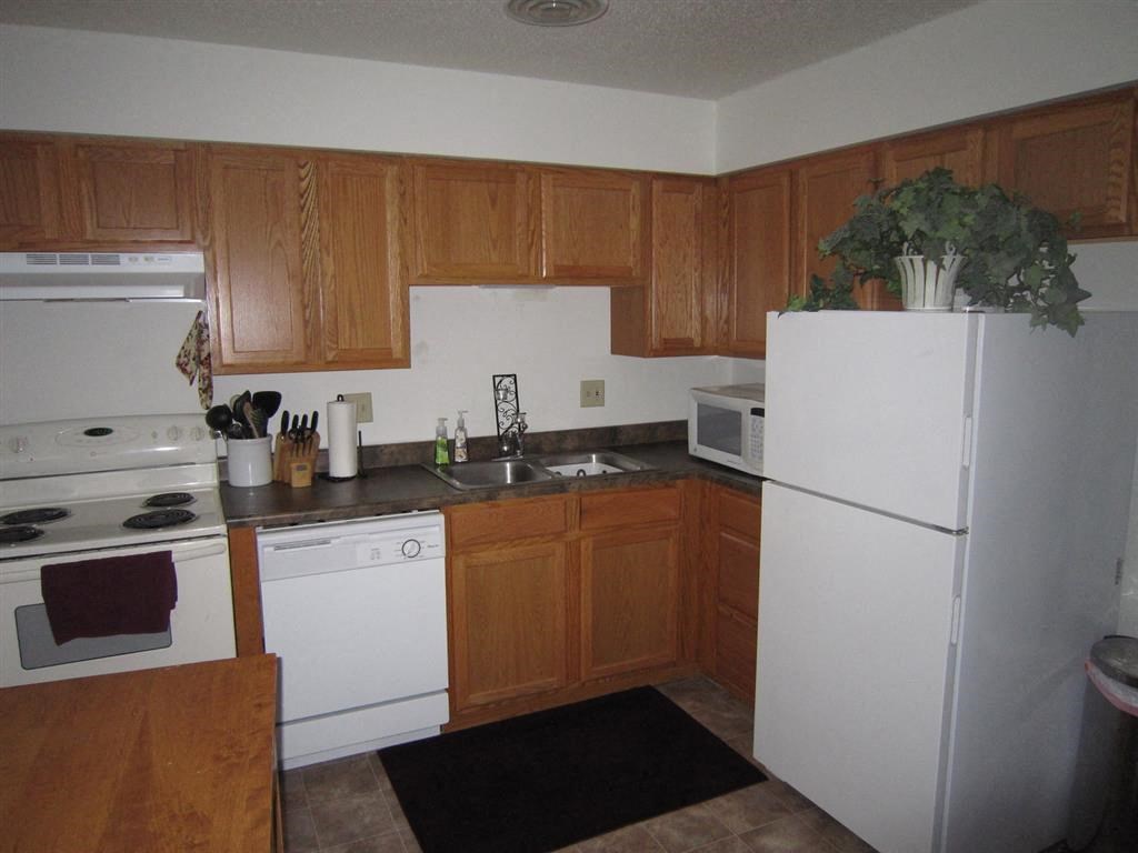 a kitchen with a white refrigerator freezer next to a stove top oven