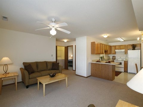 a living room and kitchen with a couch and a ceiling fan