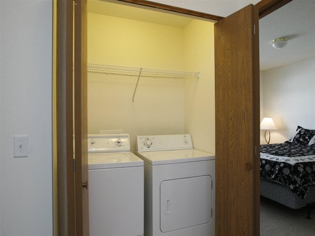 a washer and dryer are in a room with a bed in the background