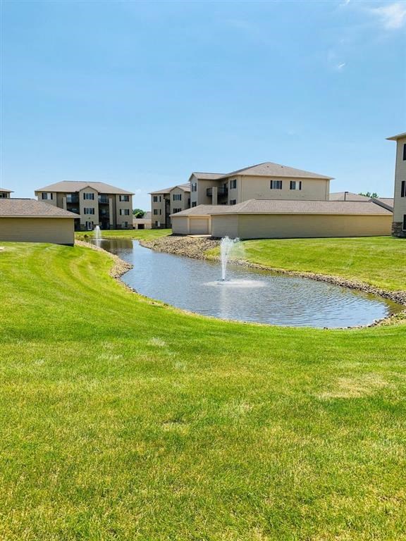 a fountain in the middle of a grassy area with houses in the background
