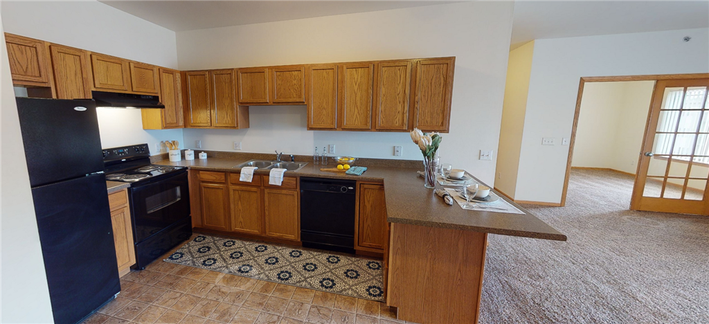 a kitchen with a black refrigerator freezer next to a stove top oven