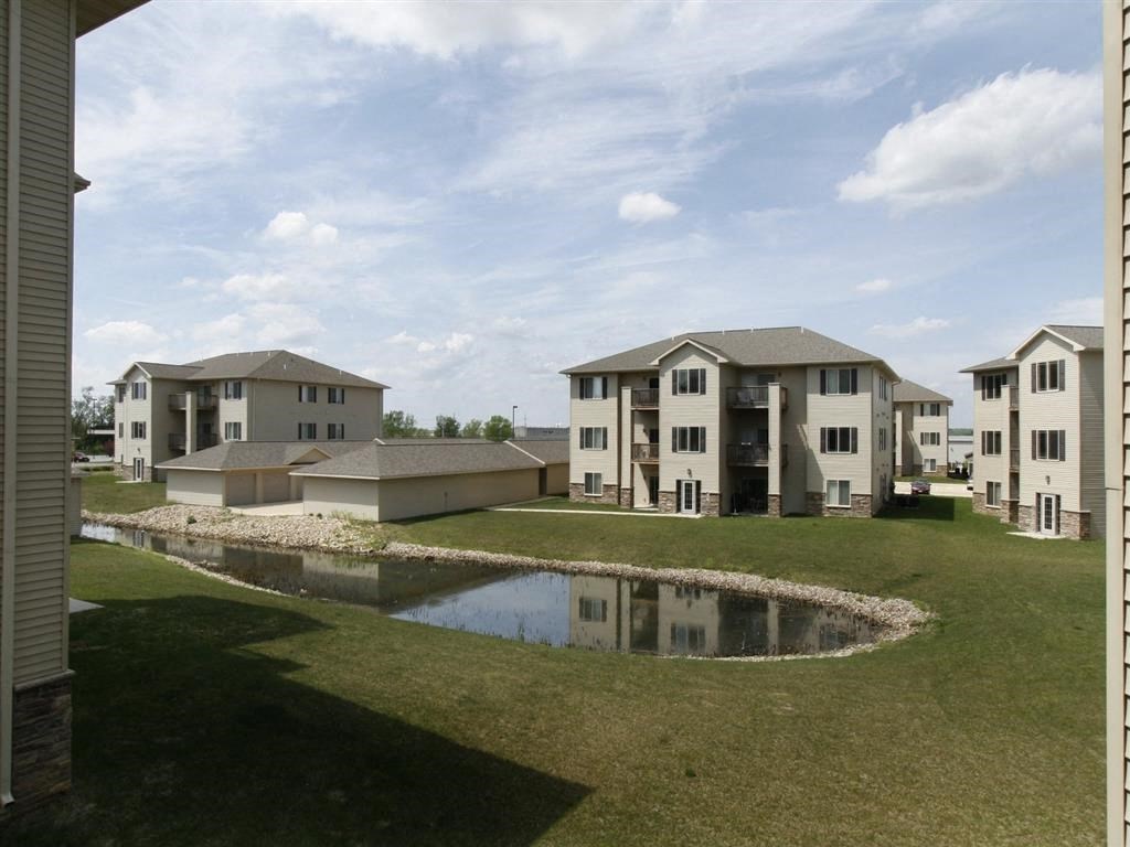 a view of an apartment complex with a pond in the foreground