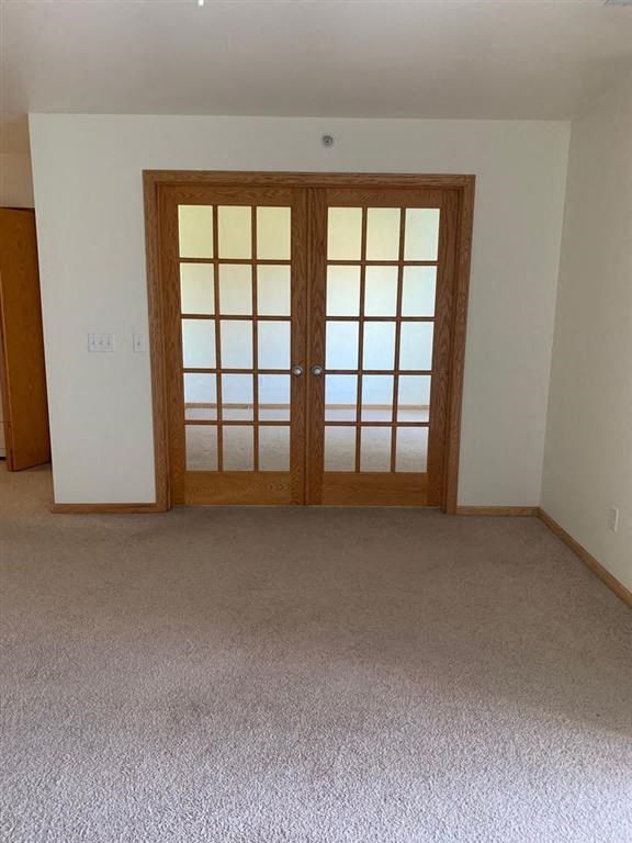 an empty room with two doors and a carpeted floor