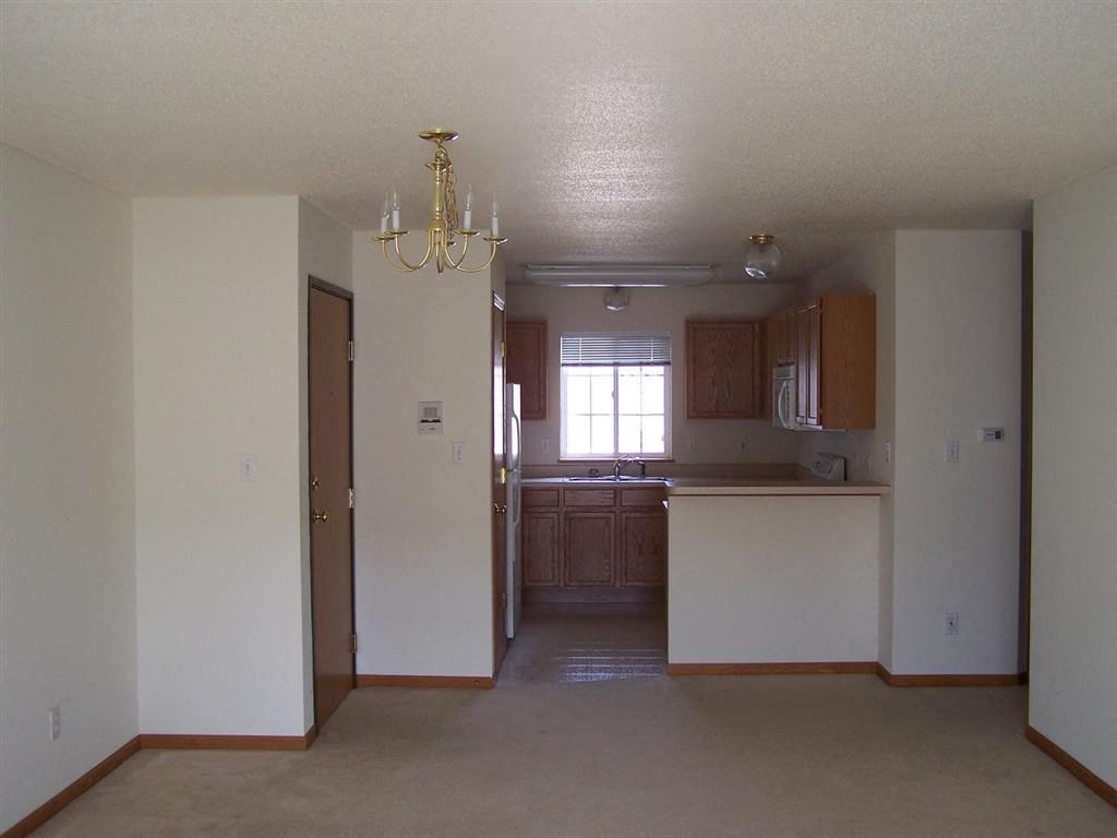 an empty kitchen and living room with a chandelier