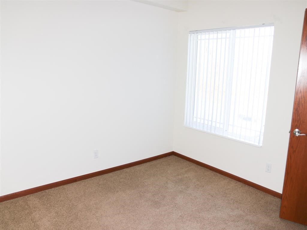 a bedroom with white walls and a window
