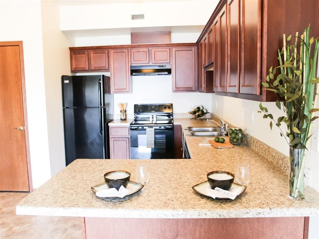 a kitchen with a black refrigerator freezer next to a stove top oven