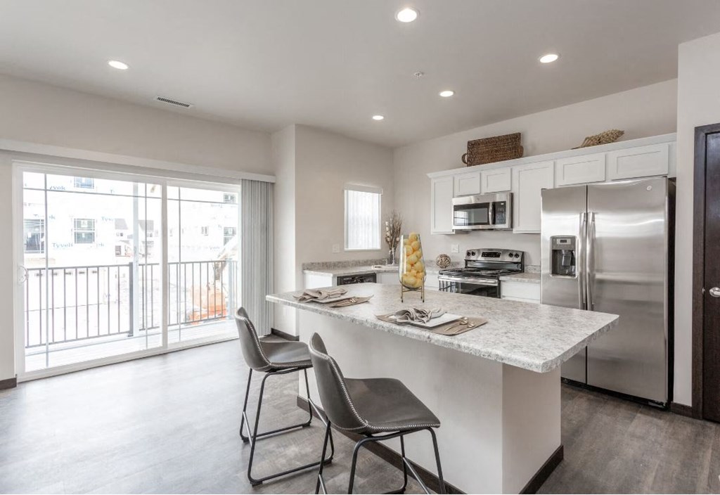 a kitchen with a marble counter top and a stainless steel refrigerator