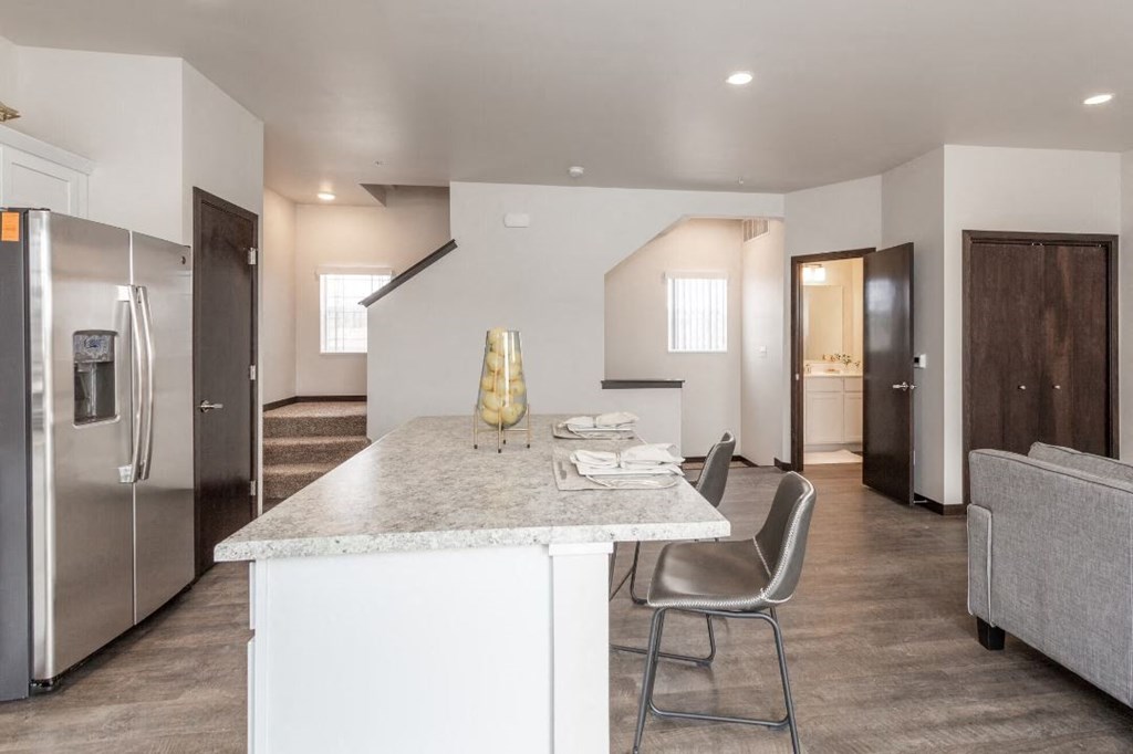 a kitchen with a marble counter top and a stainless steel refrigerator