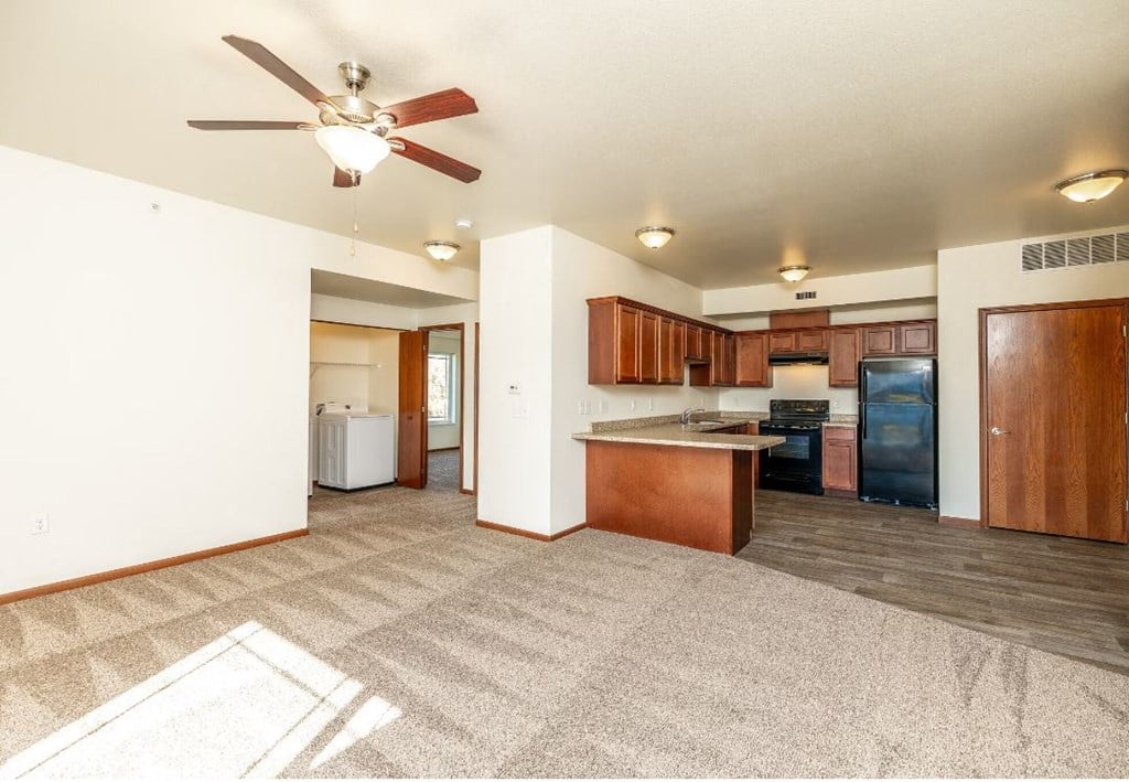a living room with a kitchen and a ceiling fan