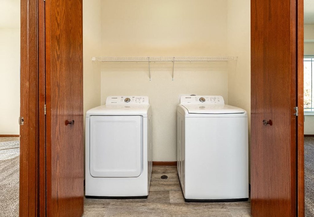 two washers and dryers in a laundry room with a wooden door