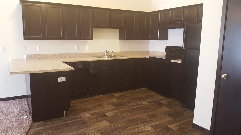 a kitchen with dark cabinets and a wooden floor