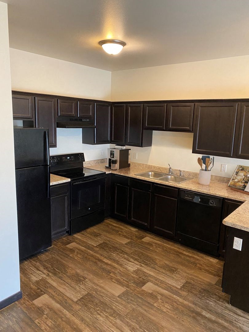 a kitchen with dark cabinets and a wooden floor