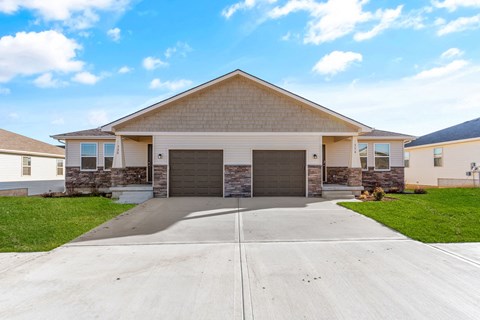 a house with two garage doors in front of a driveway