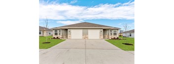 a house with two garage doors and a concrete driveway