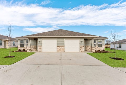 a house with two garage doors and a concrete driveway