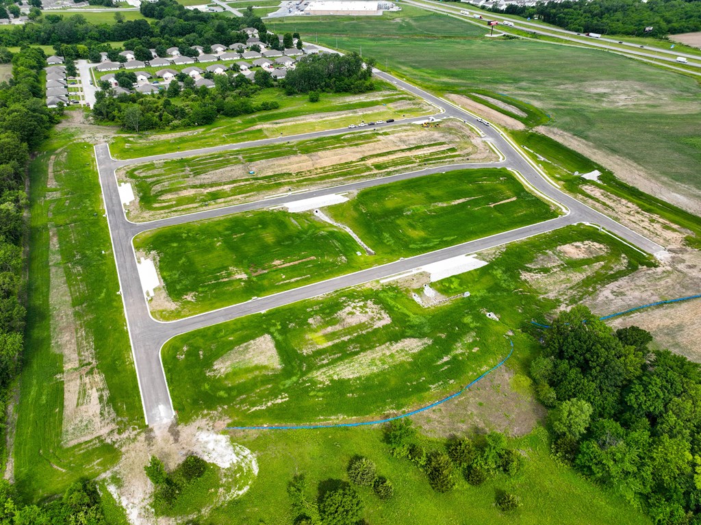 an aerial view of an empty field with green grass and trees