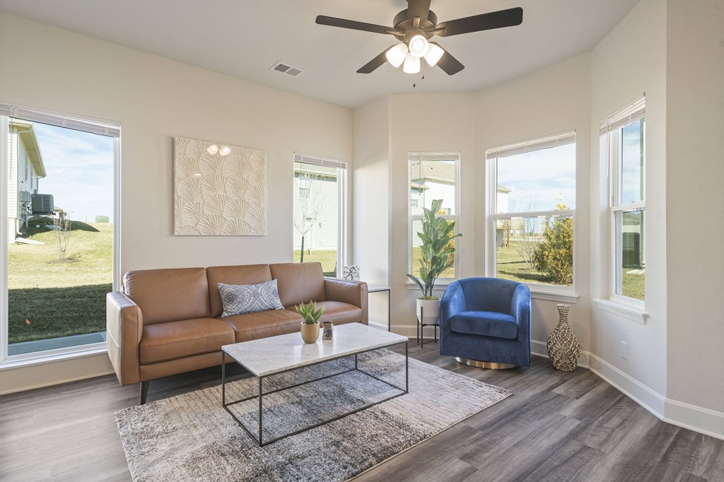a living room with a couch and a chair and a ceiling fan