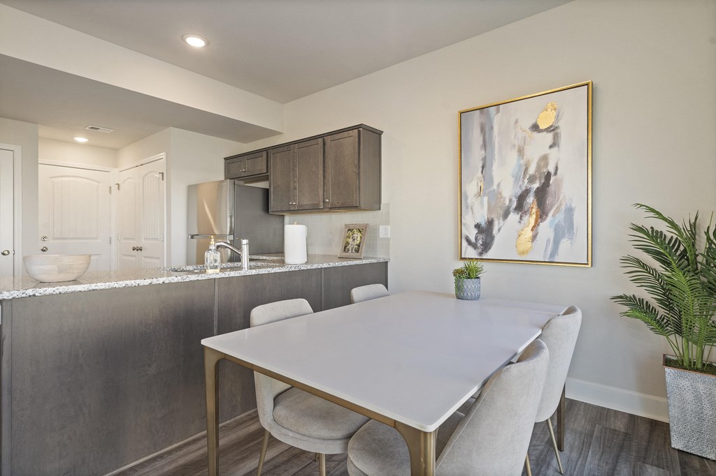 a dining area with a white table and chairs and a kitchen