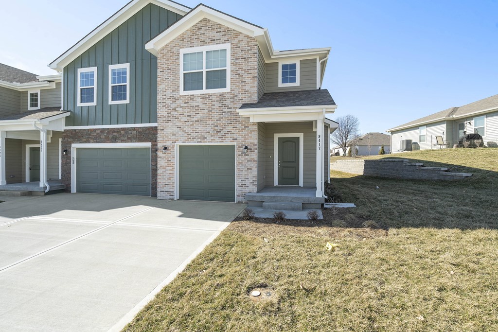 a house with two garage doors and a sidewalk in front of it