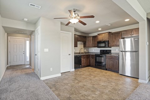 an empty kitchen with stainless steel appliances and a ceiling fan