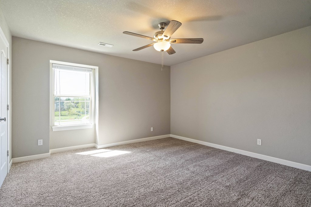 an empty living room with a ceiling fan and a window