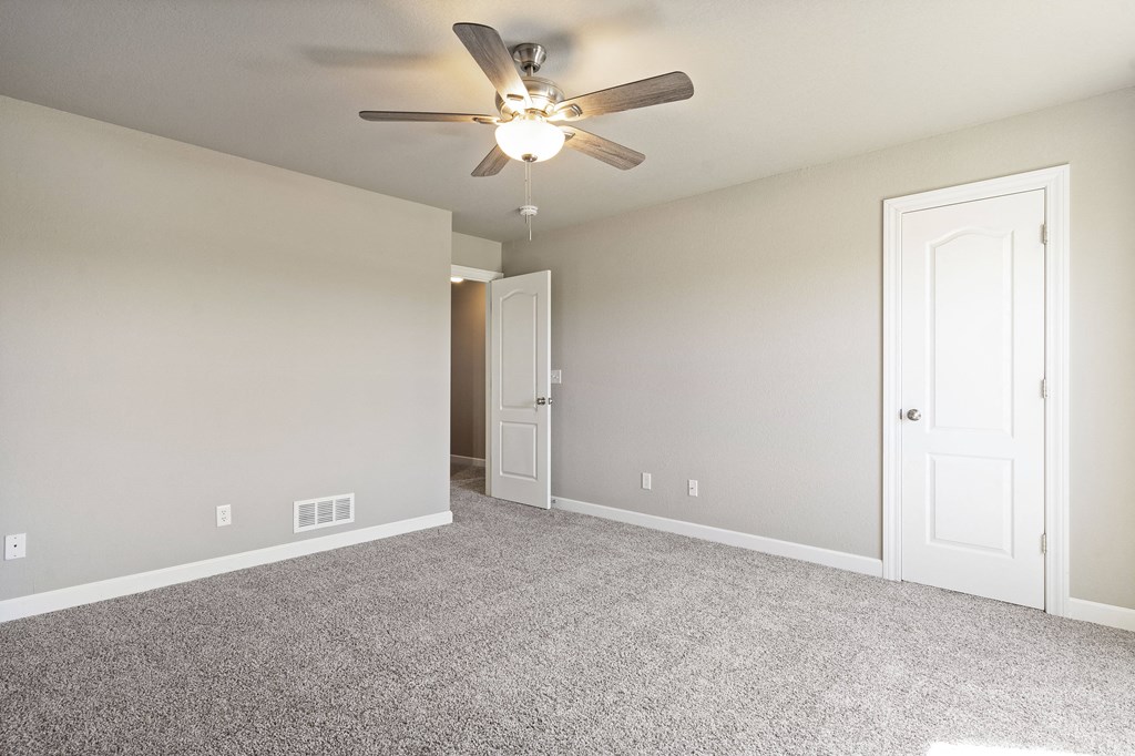 an empty living room with a ceiling fan