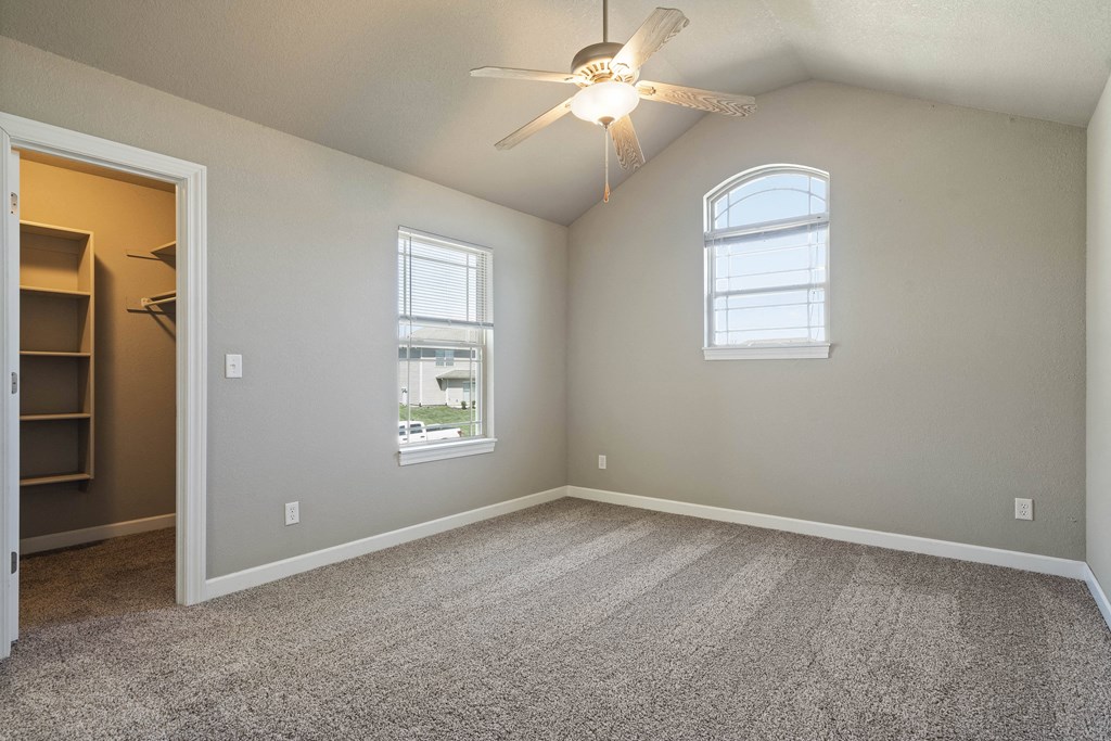 an empty bedroom with a ceiling fan and a window