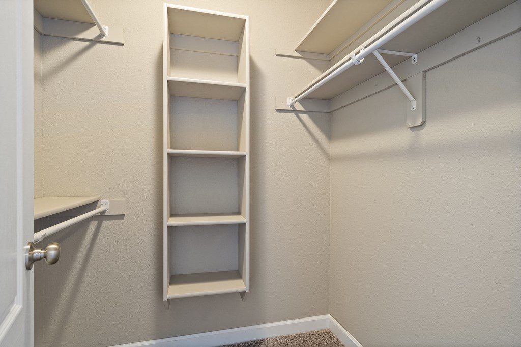 an empty closet with shelves and hooks in a bathroom