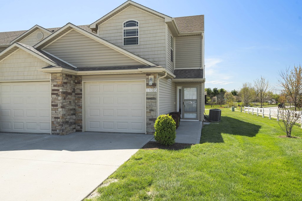 a tan house with a white garage door and a driveway