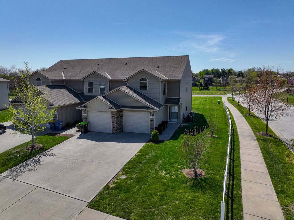 an aerial view of a house with a driveway and lawn