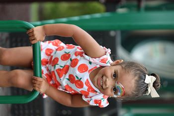 a little girl in a red and white dress holding on to a railing