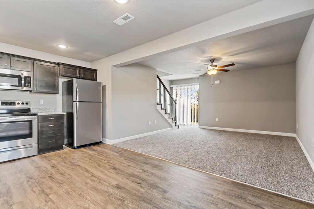 an empty kitchen with stainless steel appliances and a ceiling fan