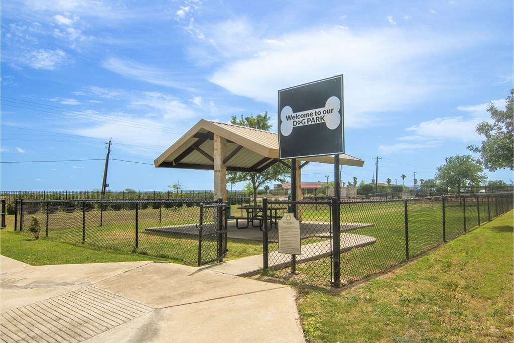 a picnic shelter in a park with a dog park in the background