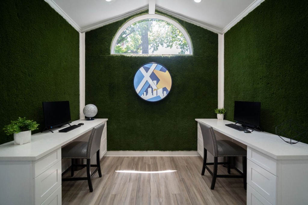 an office with a green wall and two white desks