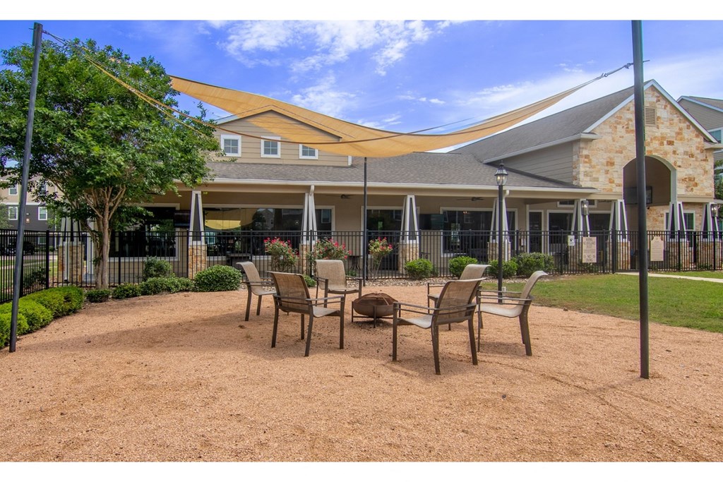 a patio with chairs and a fire pit in front of a building